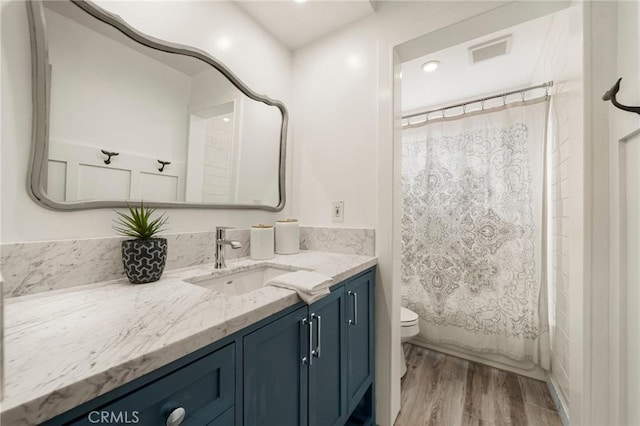 full bathroom featuring vanity, hardwood / wood-style floors, shower / bath combination with curtain, and toilet