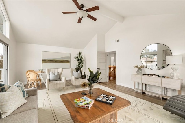 living room with beam ceiling, a healthy amount of sunlight, high vaulted ceiling, and light wood-type flooring