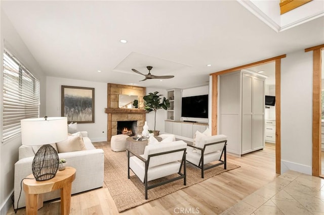 living room with a fireplace, ceiling fan, and light hardwood / wood-style floors