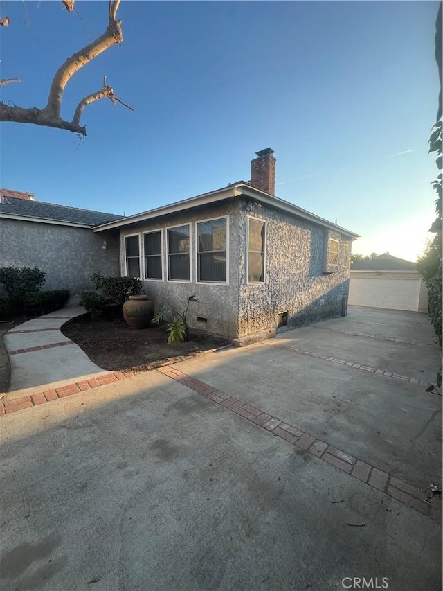 view of property exterior with crawl space, stucco siding, and a chimney