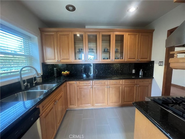kitchen featuring a sink, dark stone countertops, tasteful backsplash, wall chimney range hood, and dishwasher