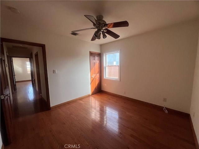 unfurnished bedroom with ceiling fan and dark wood-type flooring