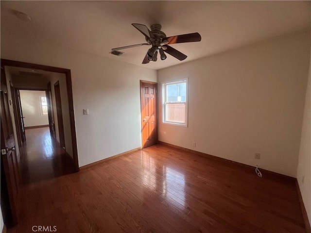 spare room with baseboards, visible vents, wood finished floors, and a ceiling fan