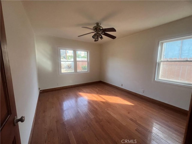 unfurnished room featuring ceiling fan, wood finished floors, and baseboards