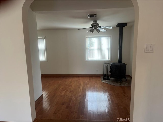 unfurnished living room featuring a wood stove, a ceiling fan, visible vents, and a wealth of natural light