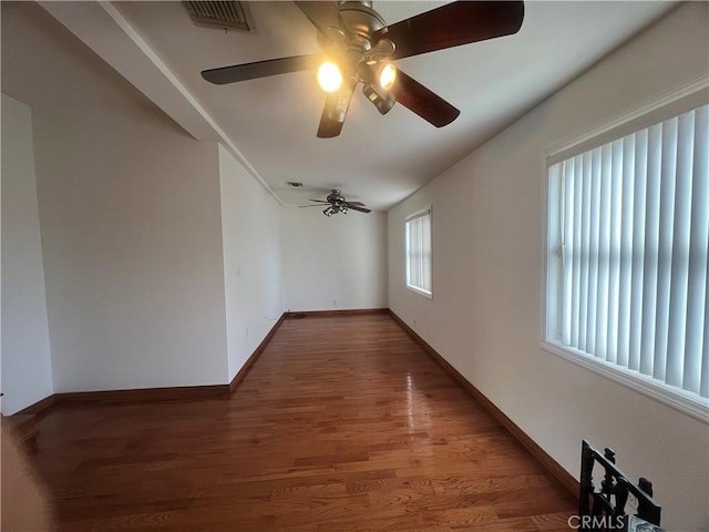 empty room with visible vents, ceiling fan, wood finished floors, and baseboards