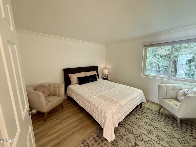 bedroom with ornamental molding and hardwood / wood-style flooring