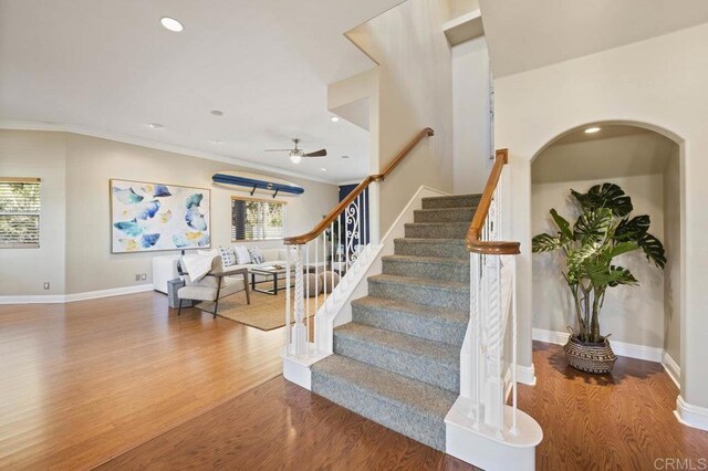 stairway with ceiling fan, ornamental molding, and hardwood / wood-style floors