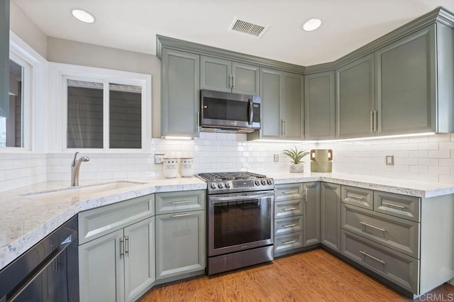 kitchen featuring sink, appliances with stainless steel finishes, light hardwood / wood-style flooring, and tasteful backsplash