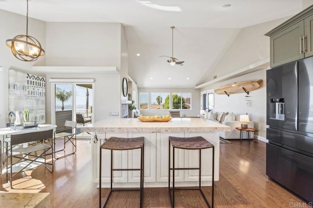 kitchen with pendant lighting, black fridge, a breakfast bar area, and green cabinetry