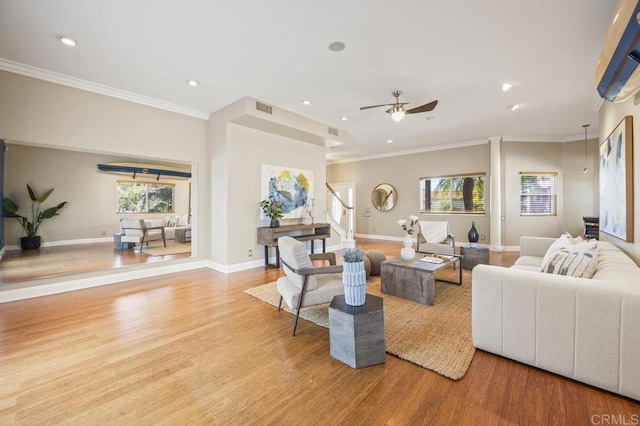 living room with a wealth of natural light, ornamental molding, and light hardwood / wood-style flooring