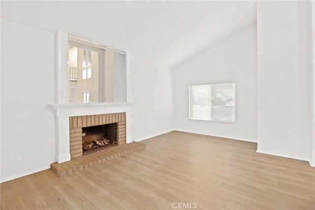 unfurnished living room with hardwood / wood-style floors, vaulted ceiling, and a fireplace