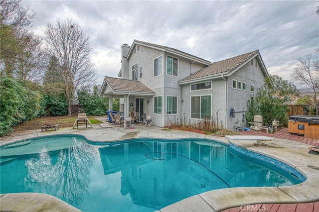 rear view of property featuring a swimming pool with hot tub and a patio