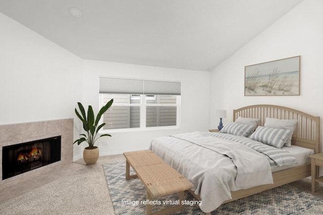 carpeted bedroom with a tile fireplace and lofted ceiling