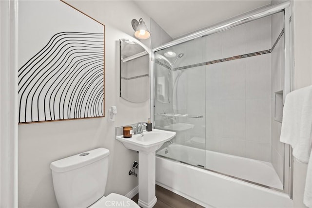 bathroom featuring toilet, bath / shower combo with glass door, and wood-type flooring