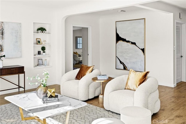 living room with built in shelves and wood-type flooring