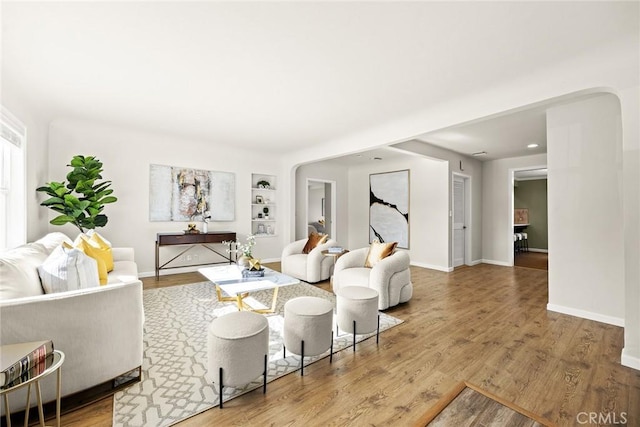 living room featuring built in shelves and hardwood / wood-style flooring