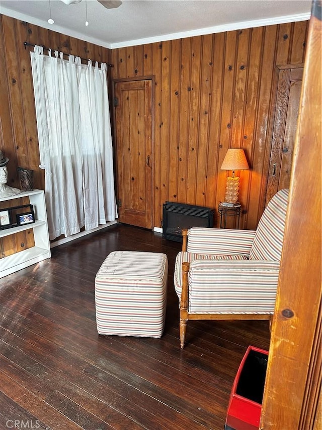 living area featuring wood-type flooring, a ceiling fan, and wood walls