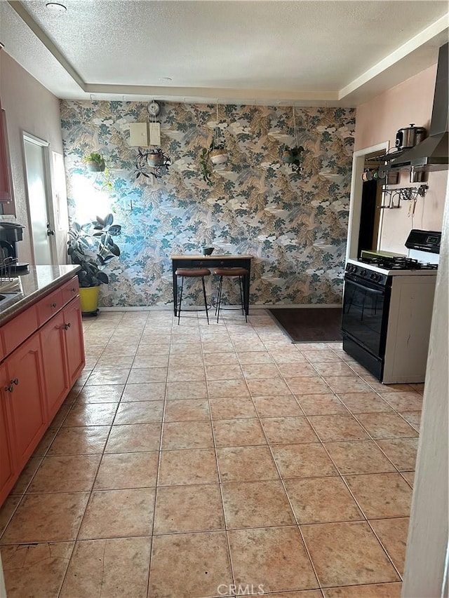 kitchen with light tile patterned floors, black range with gas cooktop, wallpapered walls, and a textured ceiling