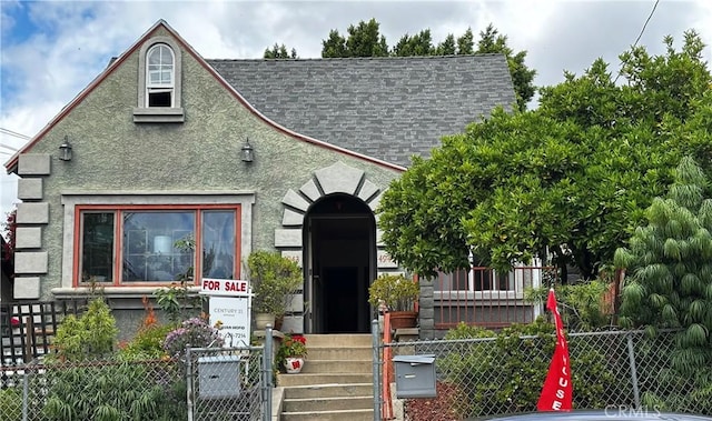 view of front of property featuring a shingled roof, a fenced front yard, and stucco siding