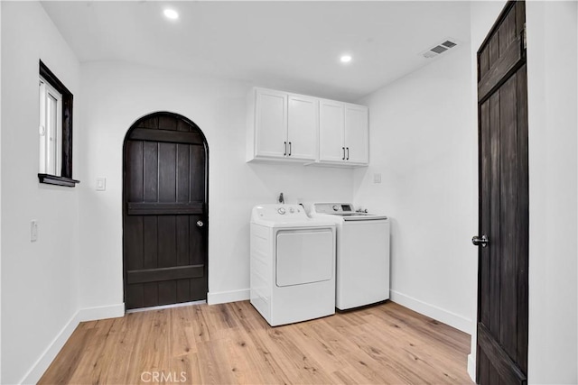 clothes washing area featuring cabinets, light hardwood / wood-style floors, and washing machine and clothes dryer