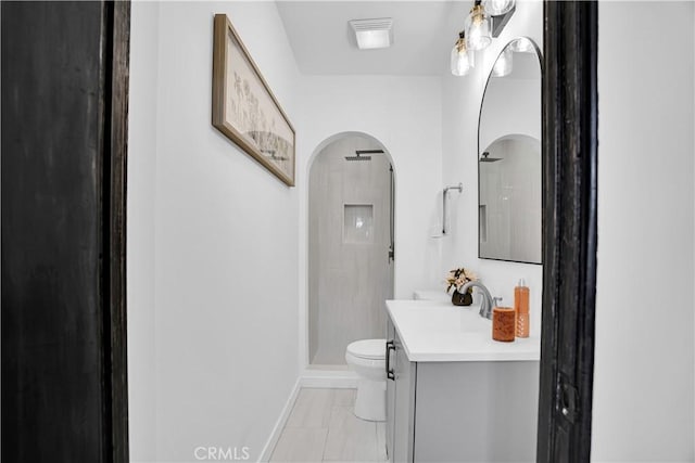 bathroom featuring toilet, vanity, and a shower