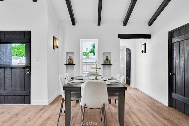 dining room with light hardwood / wood-style floors and beamed ceiling