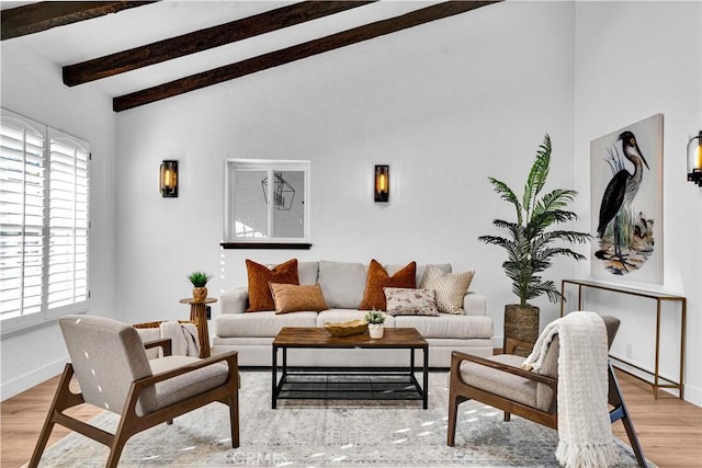 living room with lofted ceiling with beams, a wealth of natural light, and light hardwood / wood-style floors