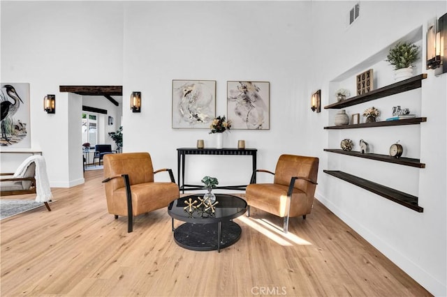 sitting room featuring light hardwood / wood-style floors and a towering ceiling