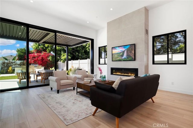 living room with a tile fireplace and light hardwood / wood-style flooring