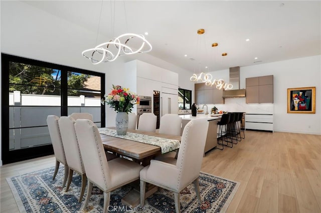 dining area featuring sink, a chandelier, and light wood-type flooring