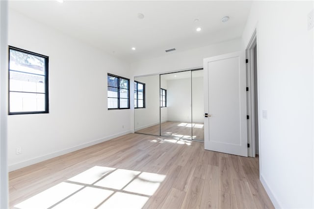 unfurnished bedroom with a closet and light hardwood / wood-style floors