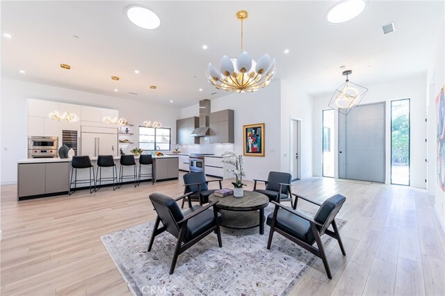 living room with light hardwood / wood-style floors, plenty of natural light, and an inviting chandelier