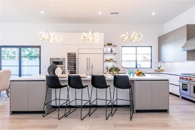 kitchen with decorative light fixtures, a large island with sink, tasteful backsplash, and high end appliances