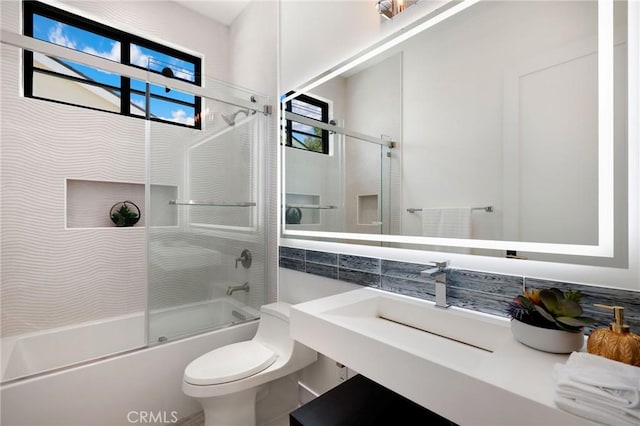 full bathroom with toilet, sink, and shower / bath combination with glass door