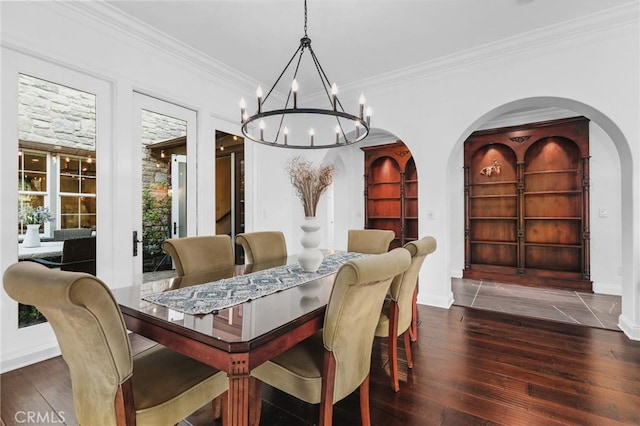 dining area featuring dark wood-type flooring, ornamental molding, and an inviting chandelier