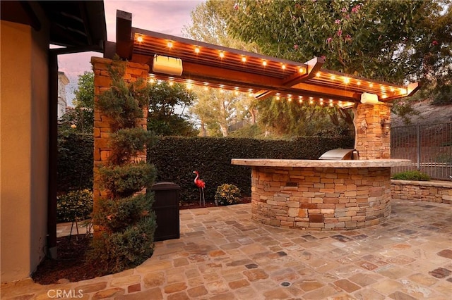 patio terrace at dusk featuring an outdoor kitchen and grilling area