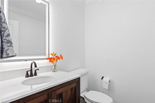 bathroom with toilet, vanity, and ornamental molding