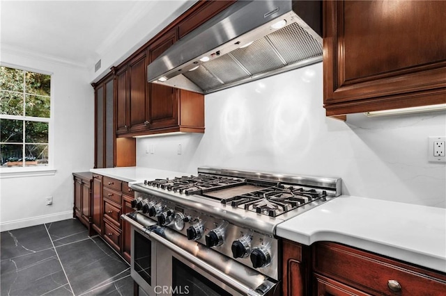 kitchen with dark tile patterned flooring, double oven range, wall chimney range hood, and ornamental molding