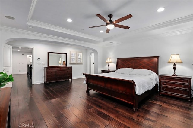 bedroom with ceiling fan, dark hardwood / wood-style flooring, crown molding, and a tray ceiling