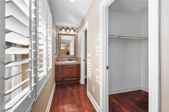 corridor with dark wood-type flooring and sink