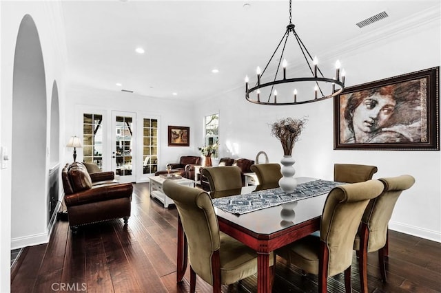 dining area featuring dark hardwood / wood-style flooring, crown molding, french doors, and a notable chandelier