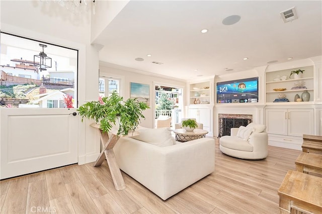 living room featuring built in features, light hardwood / wood-style flooring, and a chandelier