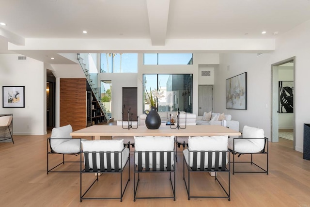 dining area with beam ceiling and light wood-type flooring