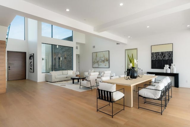 interior space featuring beam ceiling, light hardwood / wood-style flooring, and a high ceiling