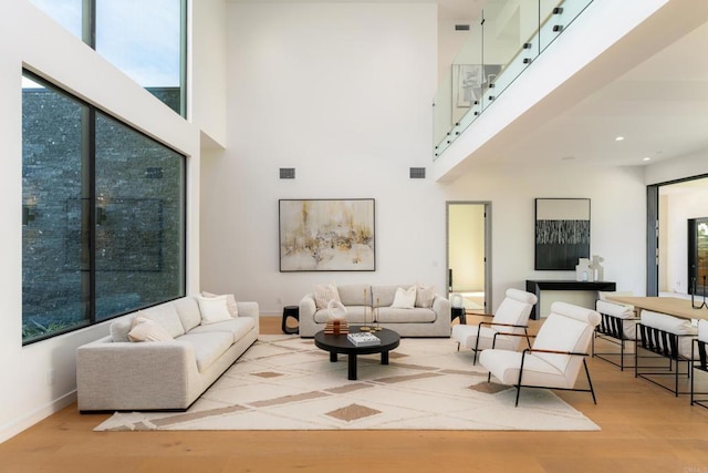 living room featuring a towering ceiling and light hardwood / wood-style flooring