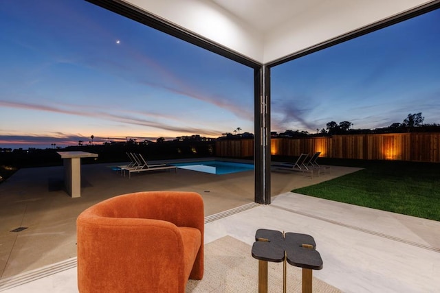 patio terrace at dusk featuring a fenced in pool