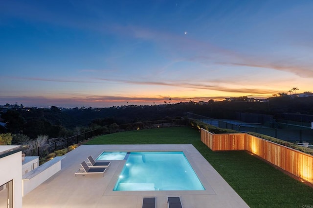 pool at dusk featuring a patio and a lawn