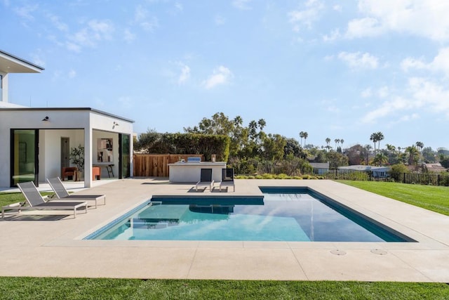 view of pool featuring a yard, a patio, and exterior kitchen