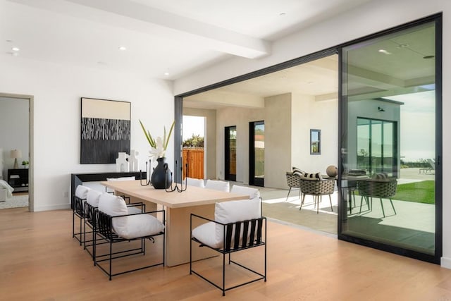 interior space featuring beamed ceiling, a kitchen breakfast bar, and light wood-type flooring